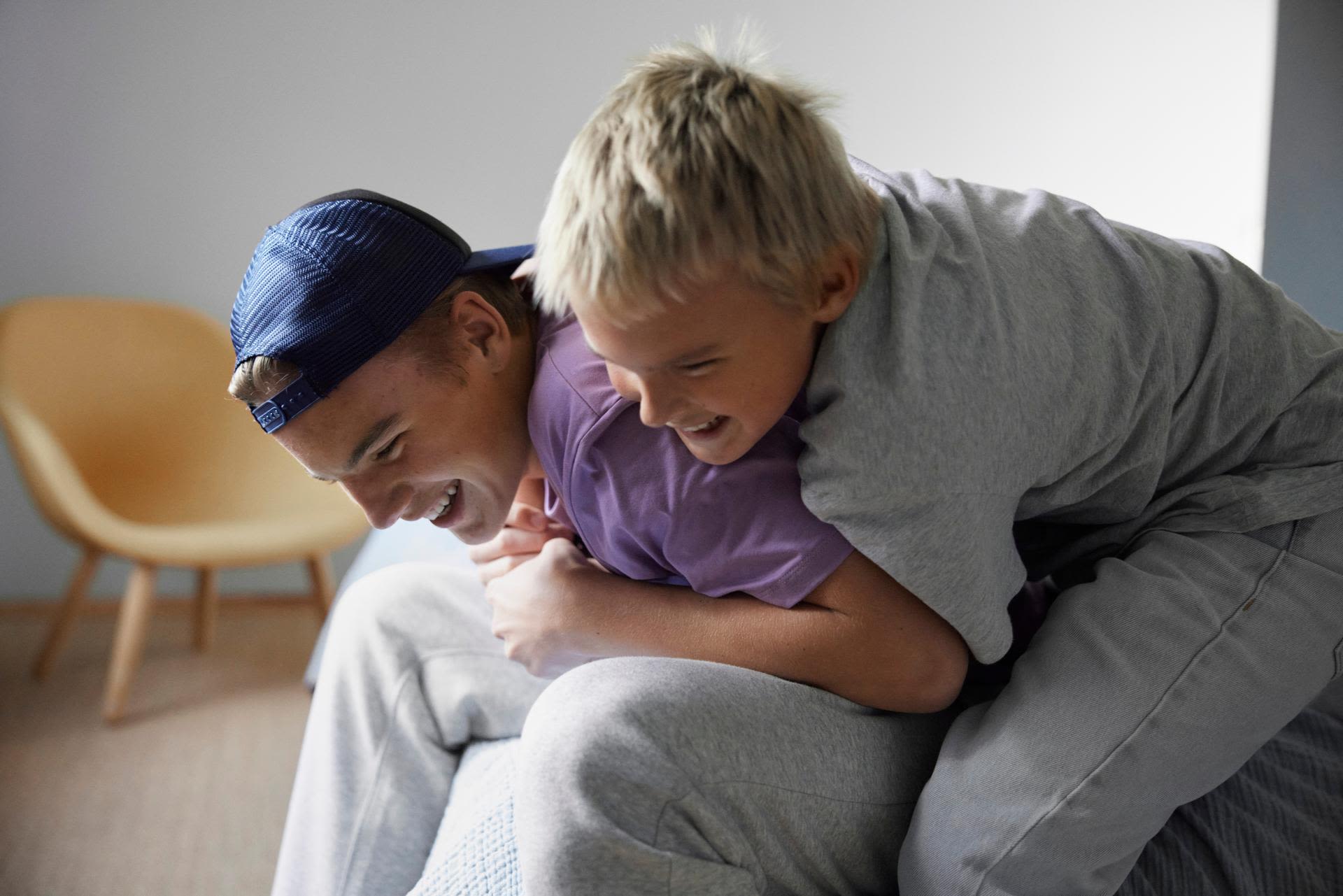 Två bröder i tonåren som skojbråkar och skrattar med varandra hemma.