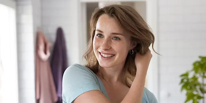 En tjej fixar håret i ett badrum.