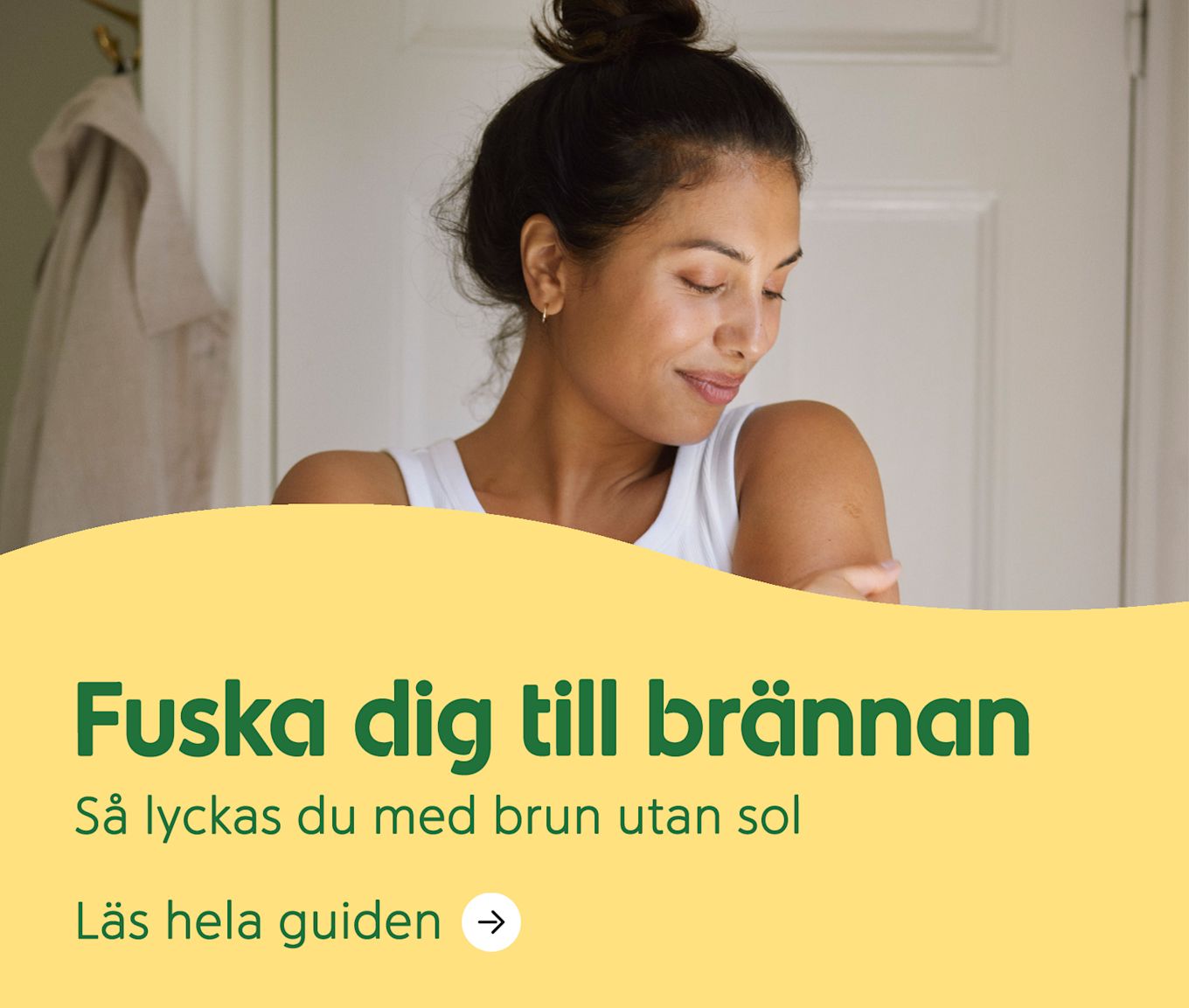 Kvinna i vitt linne smörjer sin arm och ler mjukt i ett ljust rum med vit dörr i bakgrunden. Text: Fuska dig till brännan. Så lyckas du med brun utan sol.